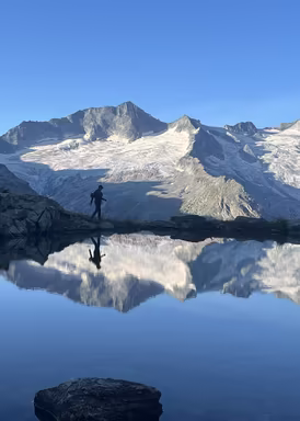 Mensch geht an einem See bei Bergpanorama entlang Weil sie da sind